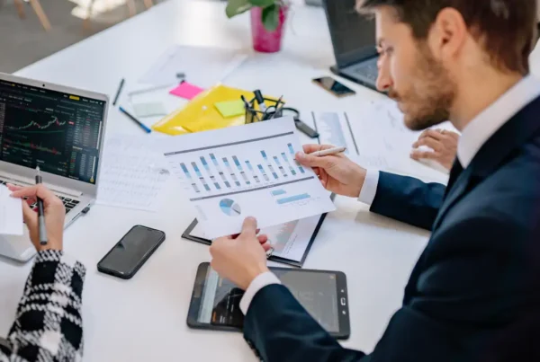 Team reviewing business charts and financial projections in an office, illustrating L‑1 new office planning and growth strategy.