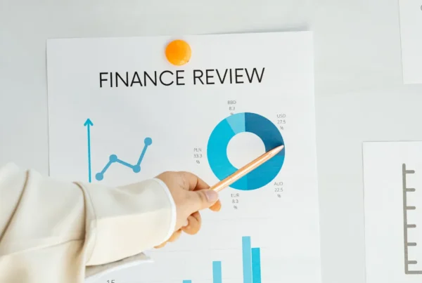 A hand pointing with a pencil to a circular finance chart labeled Finance Review on a whiteboard.