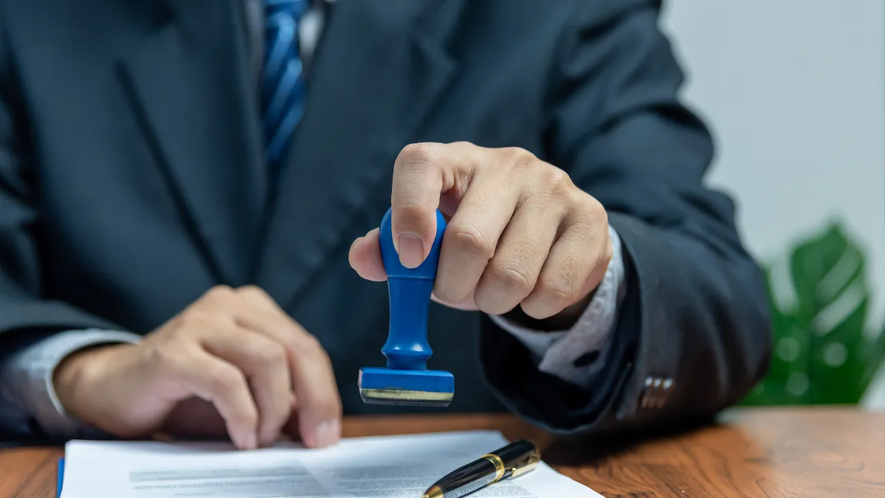 Person in a business suit stamping official documents, symbolizing U.S. visa revocation and immigration processing.