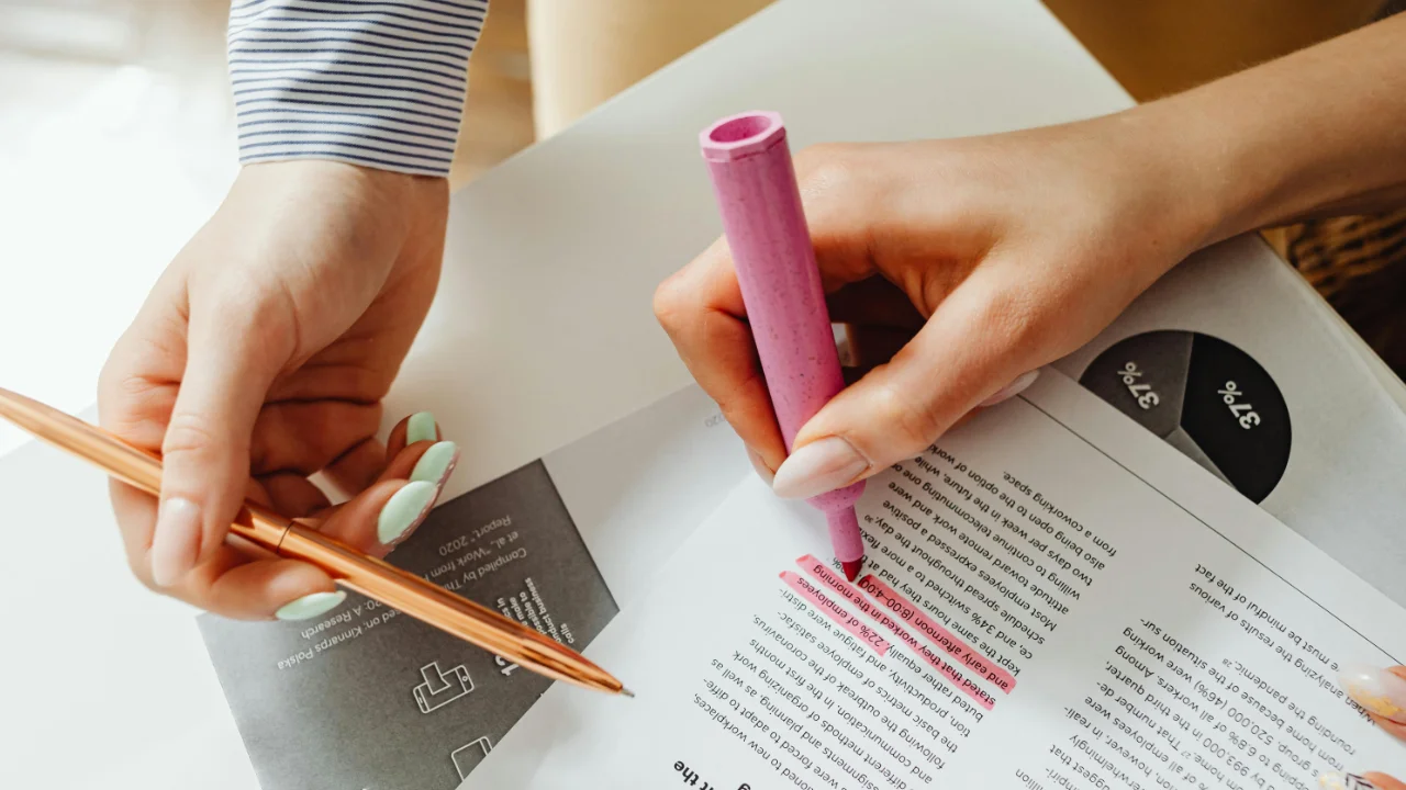 Legal professional highlighting key sections of an E-2 visa investment document with a pink marker and a gold pen.