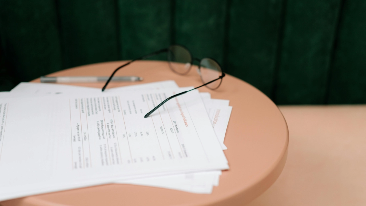 A pair of glasses resting on a stack of legal documents and business reports on a table.