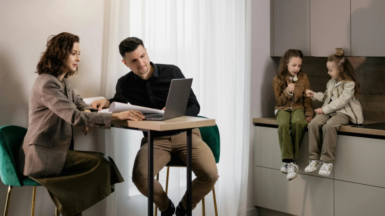E-2 investor family reviewing documents together at home with laptop and children playing in the background.