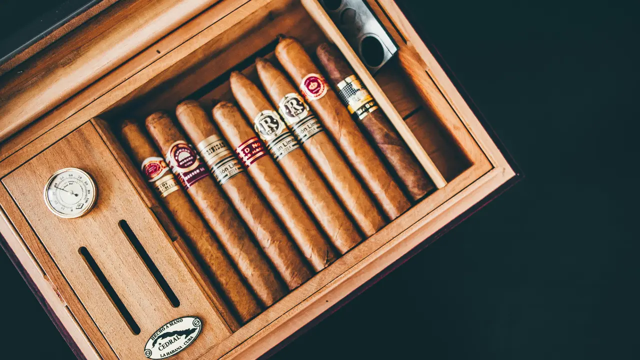 Open wooden cigar box containing neatly arranged cigars on a dark surface.