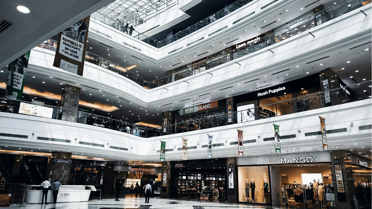 Interior view of a modern multi-level shopping mall with retail stores and open walkways.