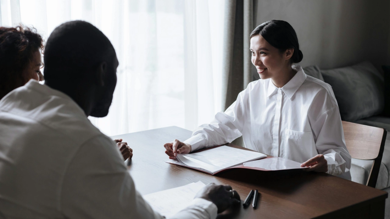 A USCIS officer reviewing application documents with a couple during a marriage-based green card interview.