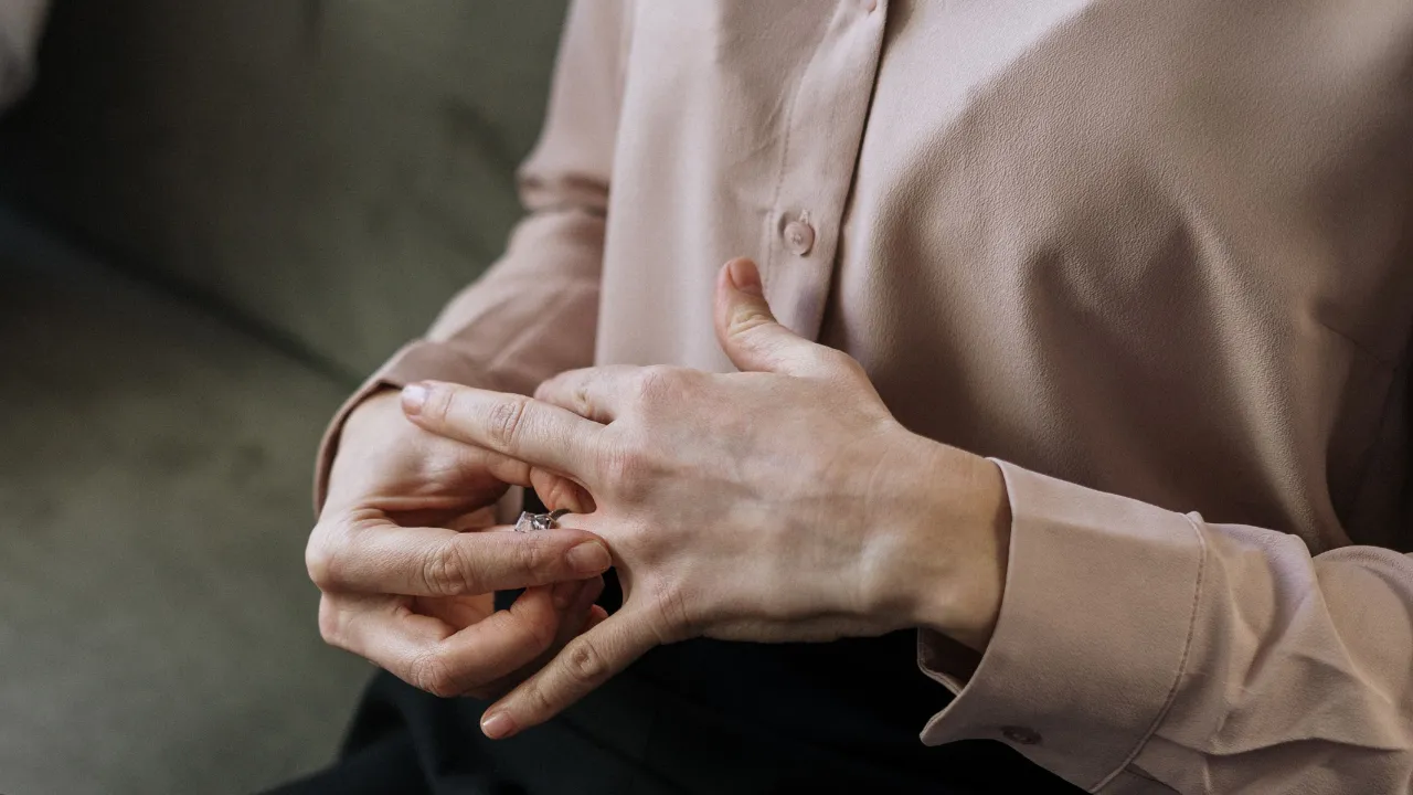 A close-up of a person hesitantly removing a wedding ring, illustrating the divorce impact on U.S. immigration status.