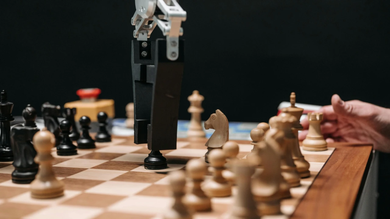 Robotic arm placing a chess piece on a chessboard with human hand nearby