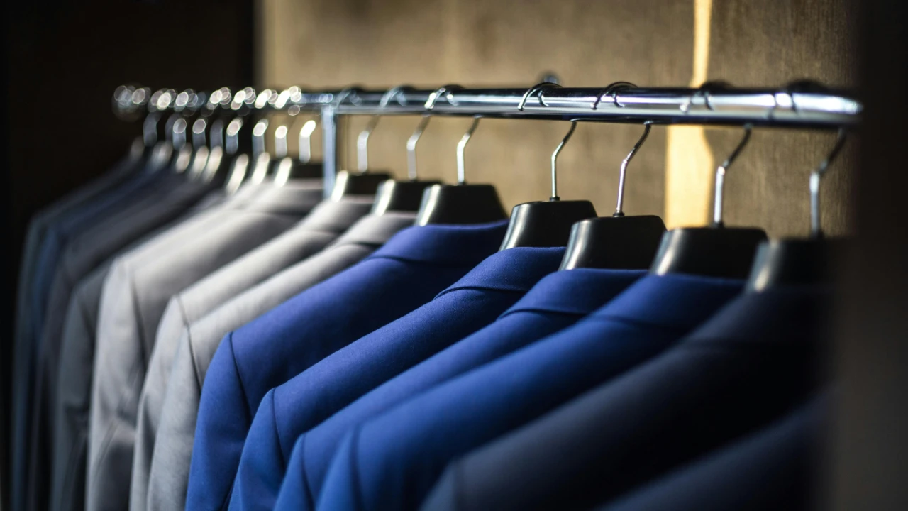 A clothing rack filled with neatly arranged suit jackets in dark and neutral tones