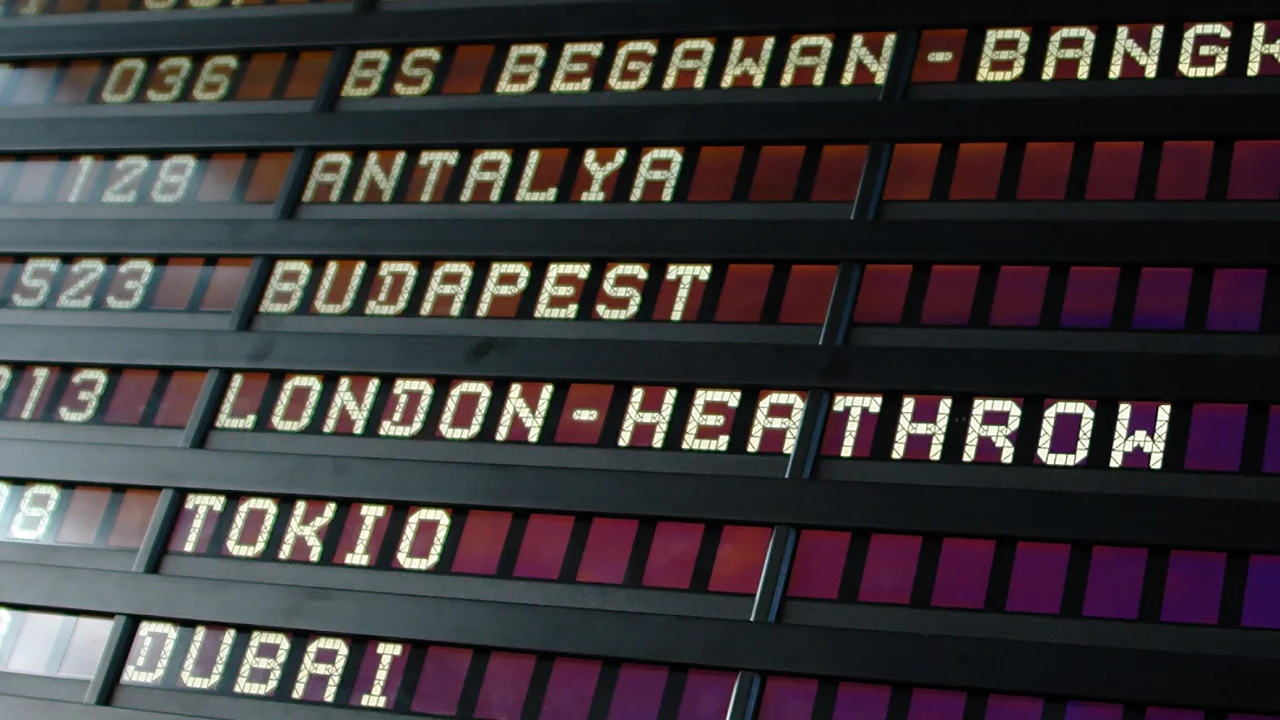 A close-up view of an airport flight departures board showing international destinations like London-Heathrow, Tokyo, and Dubai with flight times.