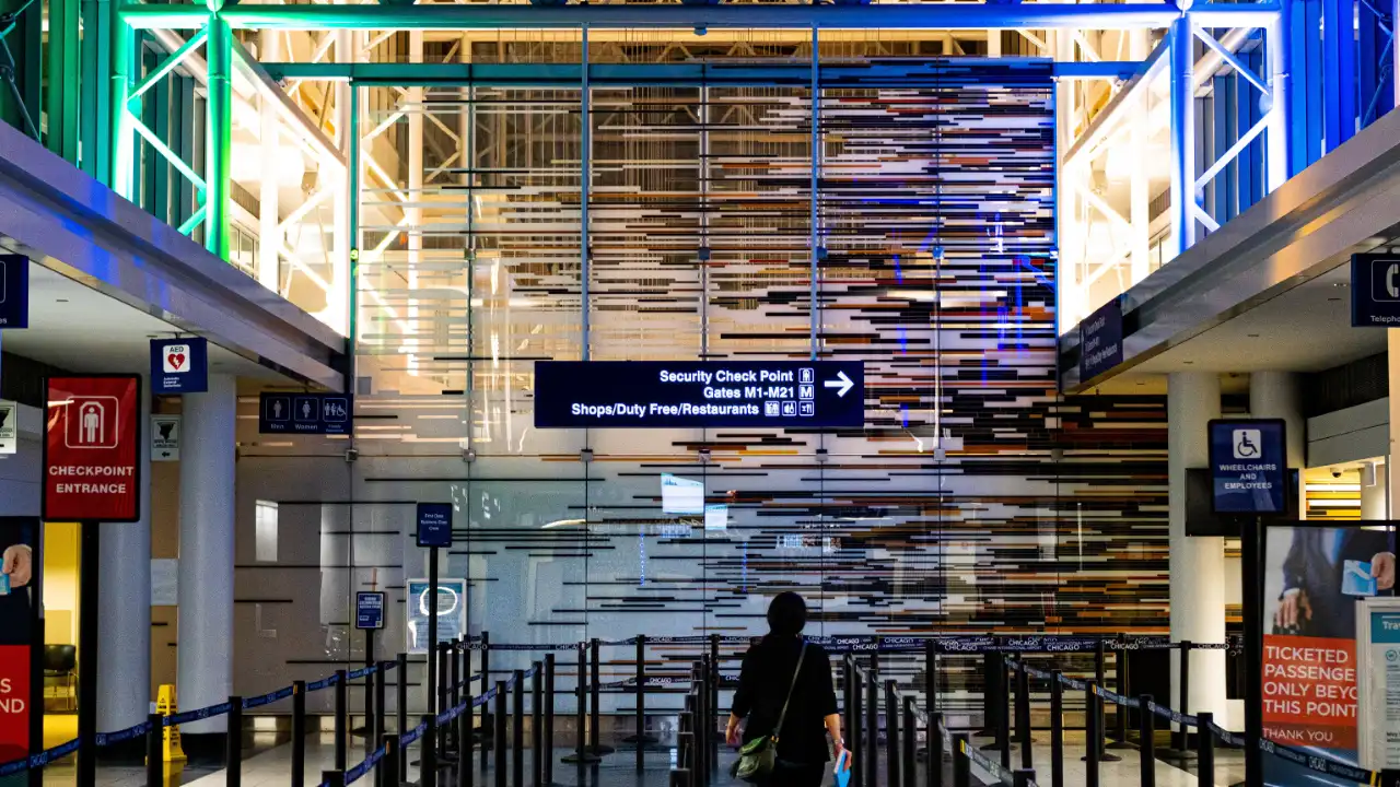 Airport security checkpoint with traveler approaching CBP inspection area