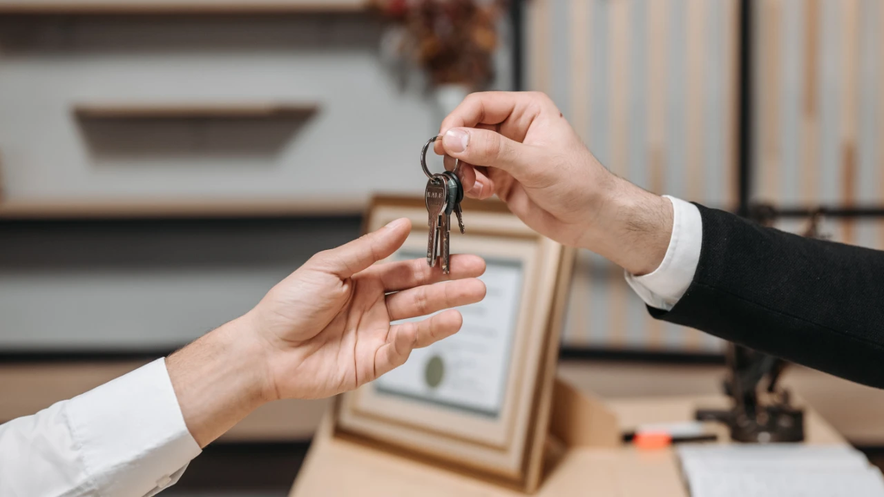 Seller handing business keys to a buyer across a desk, representing the transfer of ownership when buying a business for an E-2 visa.