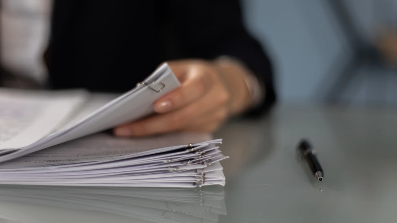 Person reviewing a stack of legal documents clipped together on a desk
