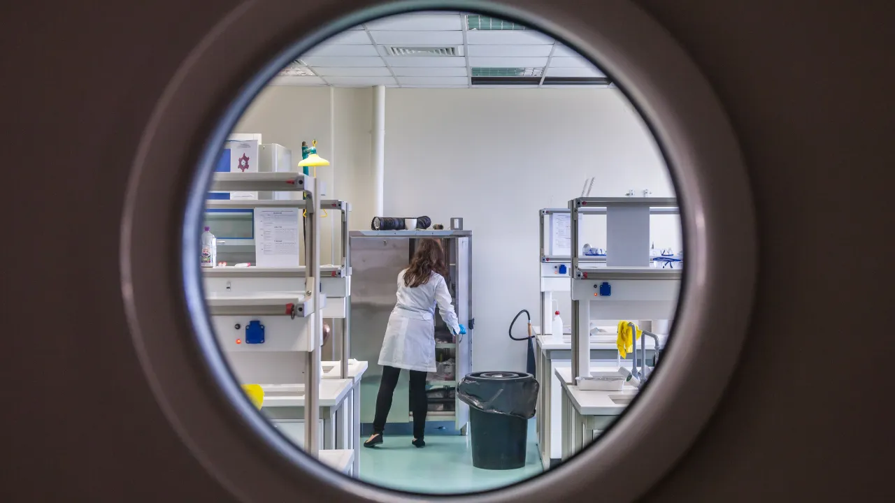 Researcher in a white lab coat viewed through a round window, representing skilled professionals who can use the O-1A visa as an alternative to the NIW.