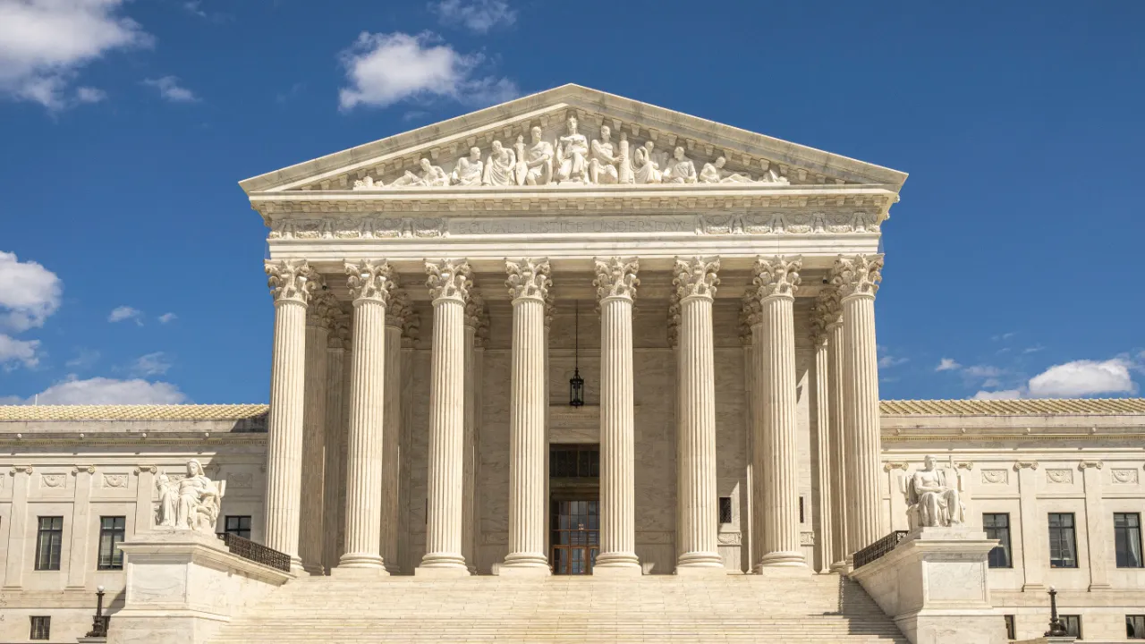 Front facade of the United States Supreme Court building in Washington, D.C., under a clear blue sky