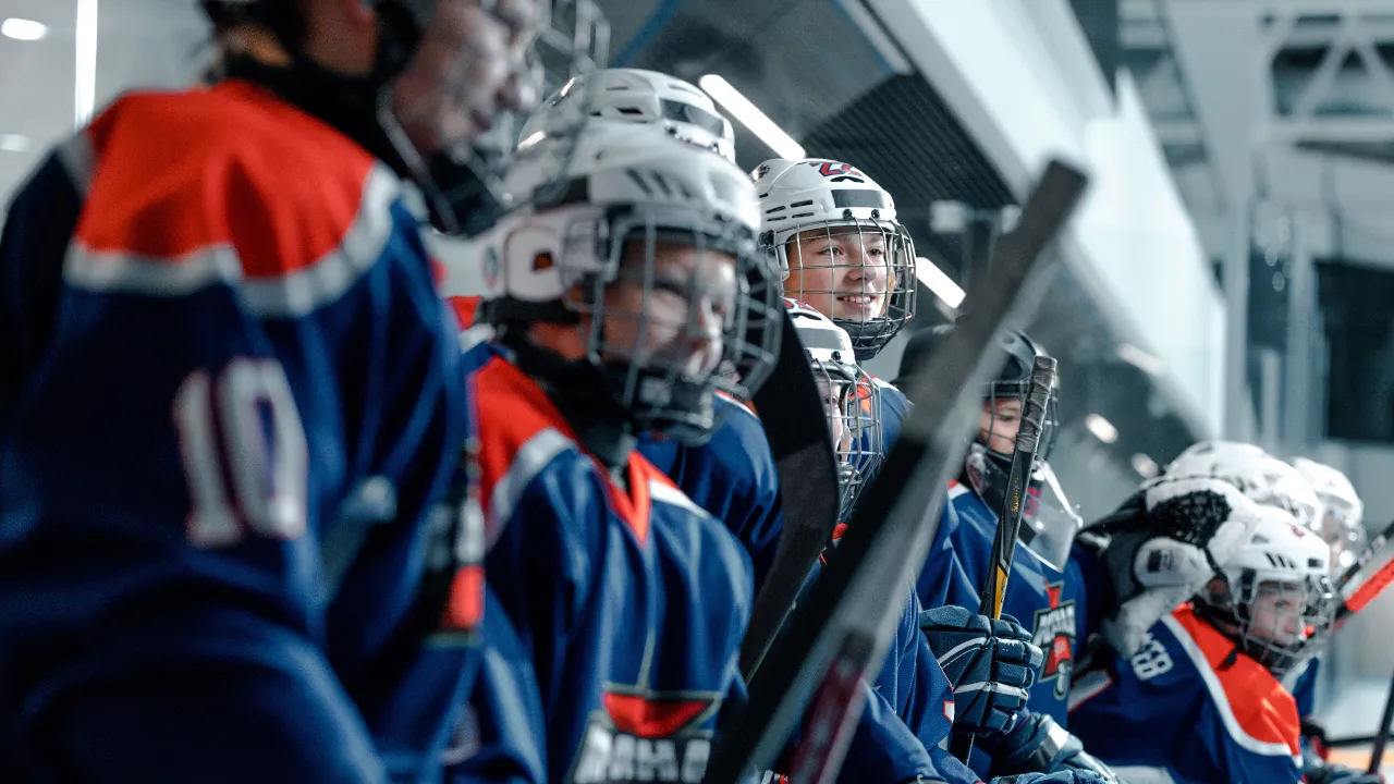 Young athletes in team uniforms lined up on a bench before a game, representing a youth sports business launched on an E-2 investor visa.