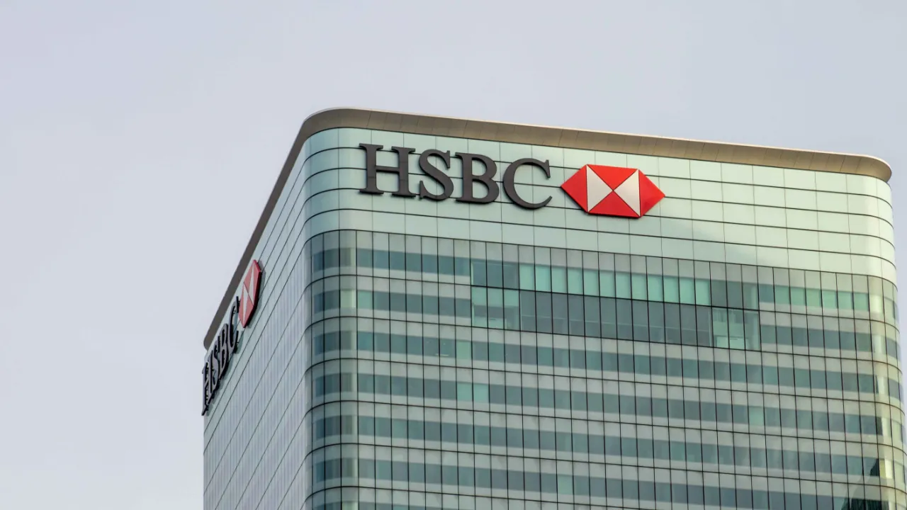 Glass office tower with a bank's corporate logo near the roofline against a pale sky