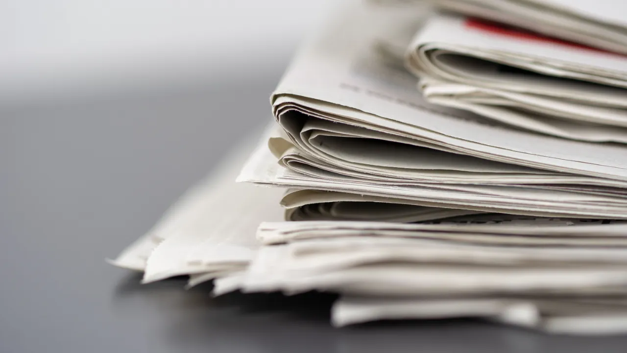 Stack of folded newspapers on a gray desk