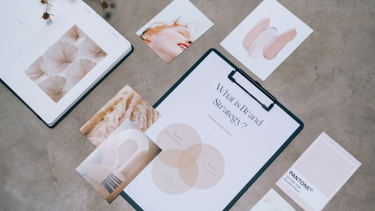 Flat lay of branding mood board cards, color swatches, and a clipboard on a concrete surface