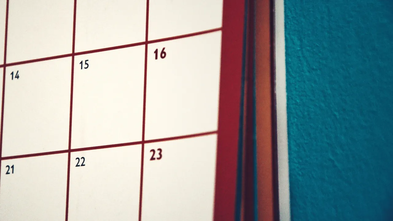 Close-up of a wall calendar with red grid lines showing dates from the 7th to the 23rd